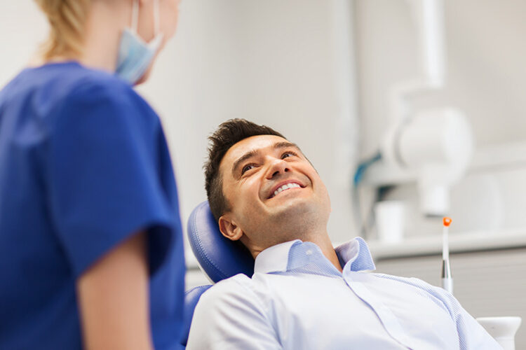 Patient in the dental chair smiling while talking to a dental assistant, representing gentle and professional tooth extractions at Deluxe Dental in Miami, Kendall, and Medley.