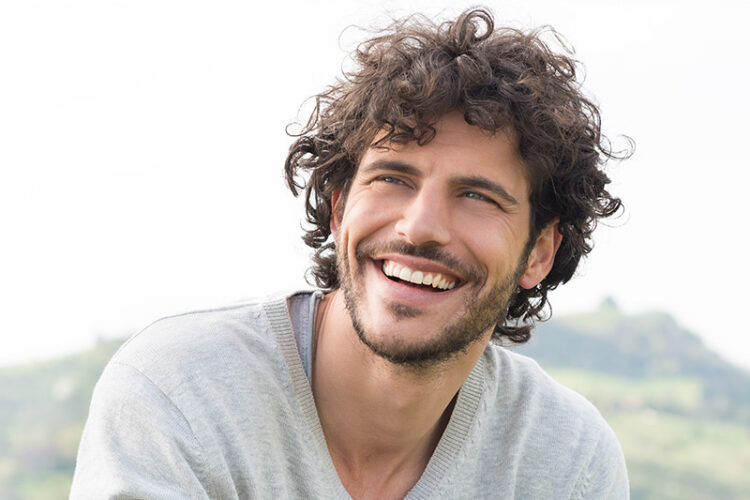 Man smiling confidently, representing the results of smile design treatment available at Deluxe Dental in Miami, Kendall, and Medley