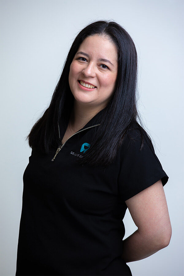 Gina, Administrator at Deluxe Dental in Miami, smiling for her professional bio photo.